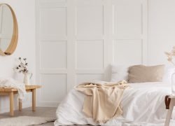 White simple bedroom design with mirror, dresser and comfortable bed with white sheets, real photo